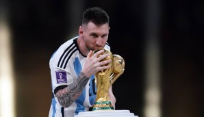 Lionel Messi küsst nach dem größten Triumph seiner Karriere seine Trophäen.